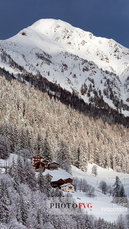 Typical mountain houses near Colle di Santa Lucia after an intense snowfall