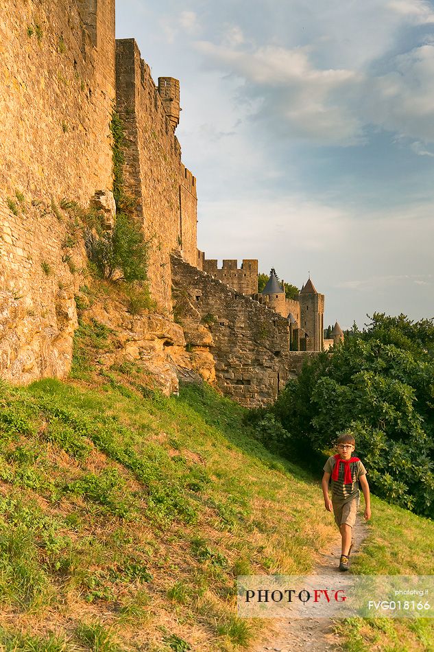 Child hiking outside the walls of the mediavel ancient city of Carcassonne at sunset