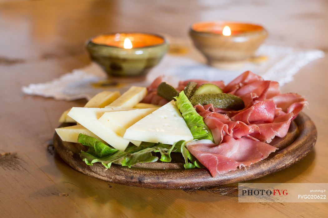 Rustic platter of alpine cheeses and cold cuts of Rinfreddo hut, Comelico, dolomites, Italy