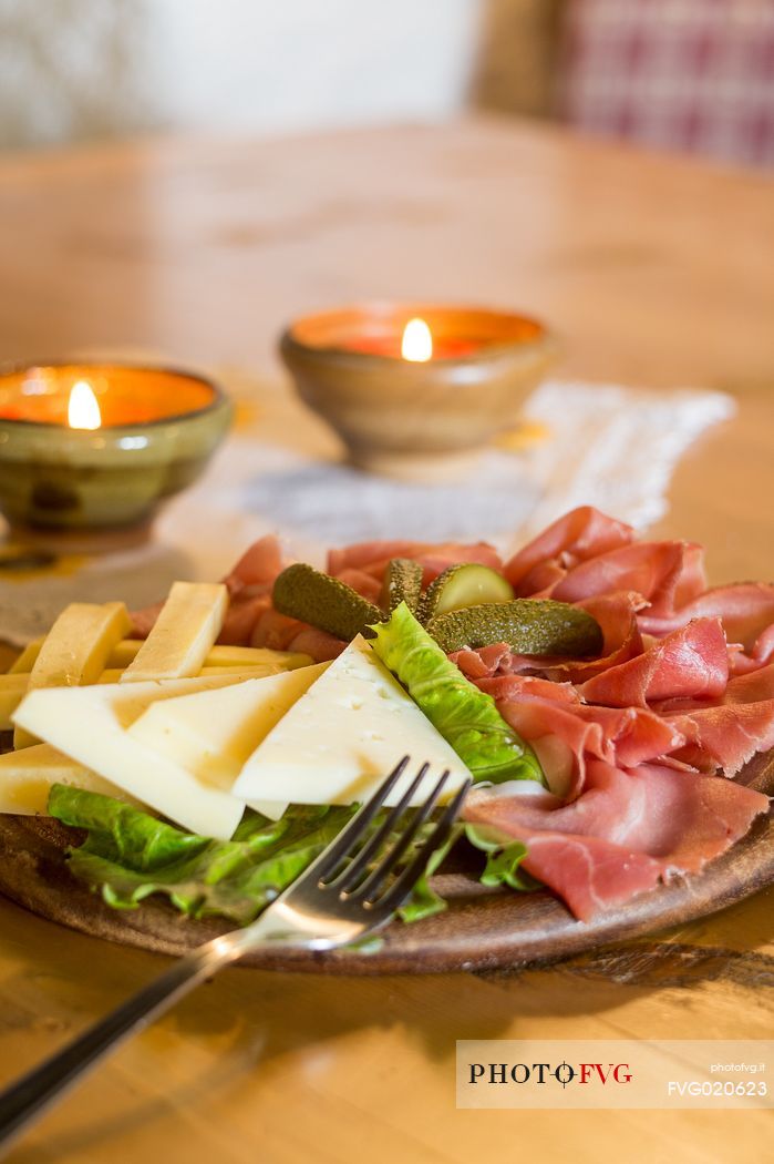 Rustic platter of alpine cheeses and cold cuts of Rinfreddo hut, Comelico, Dolomites, Italy