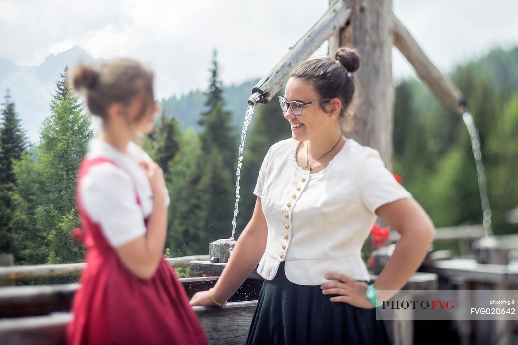 Smiling girls with a traditional dress at Rinfreddo hut, Comelico, dolomites, Italy