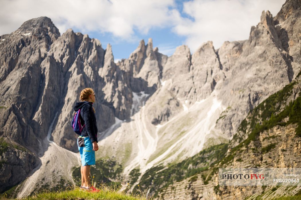 A young hiker looks the Popera group in the Sesto Dolomites from Forcella Pian della Biscia, Comelico, Italy