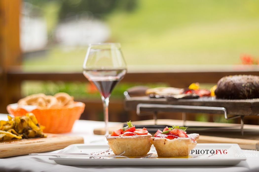 The typical cuisine of the restaurant Skay: dumplins with speck, tagliatelle with venison ragout and little cake with strawberries and custard, Comelico, Italy