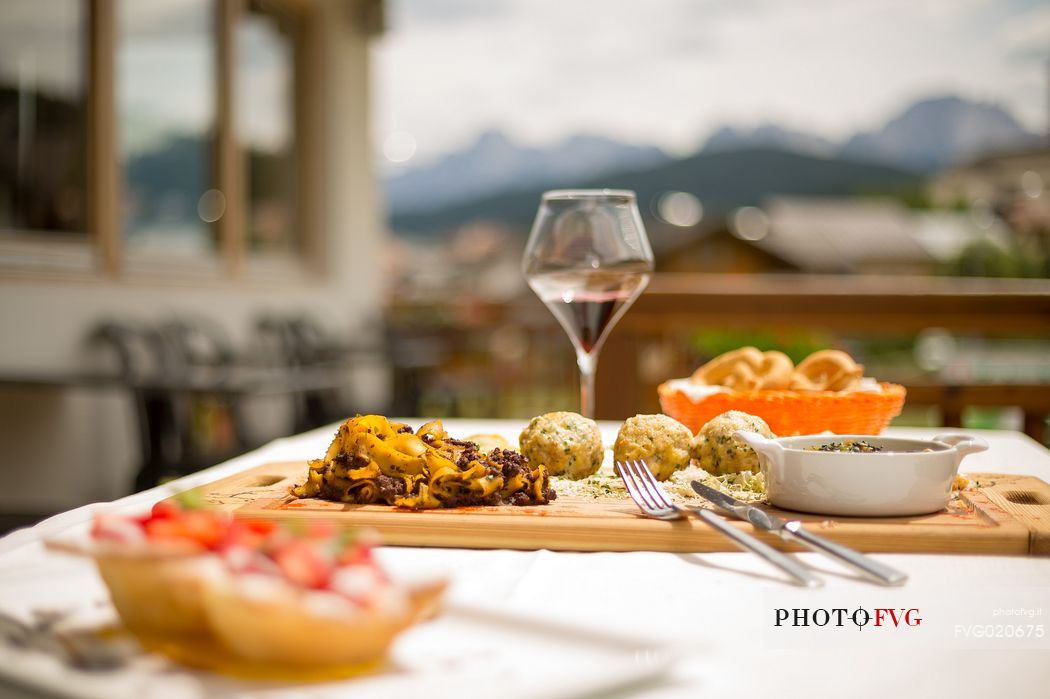 The typical cuisine of the restaurant Skay: dumplins with speck, tagliatelle with venison ragout and little cake with strawberries and custard, Cadore, Italy