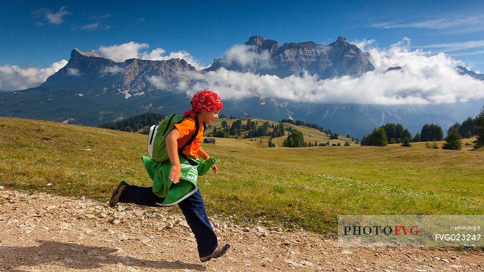 Child runs on Pralongi meadows, Badia Valley, South Tyrol, Dolomites, Italy