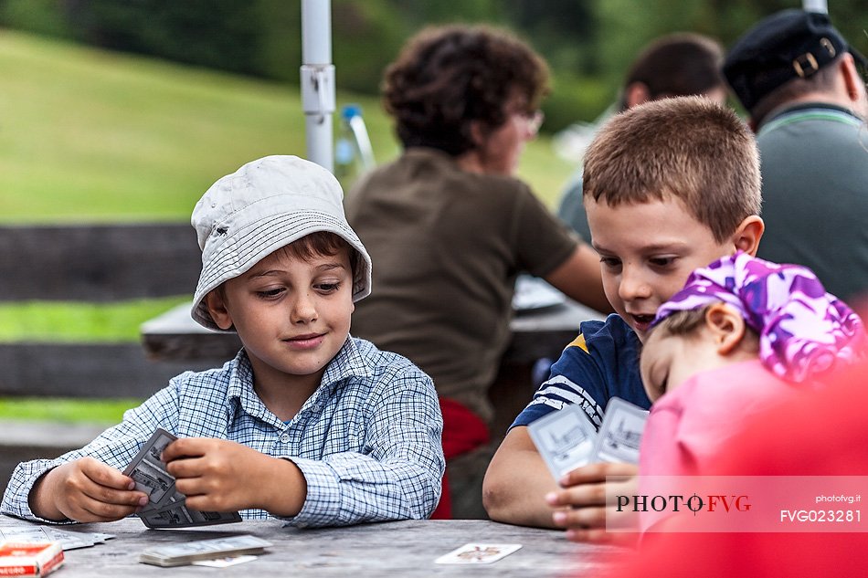 Children are playing cards at Pratopiazza hut, dolomites, Italy