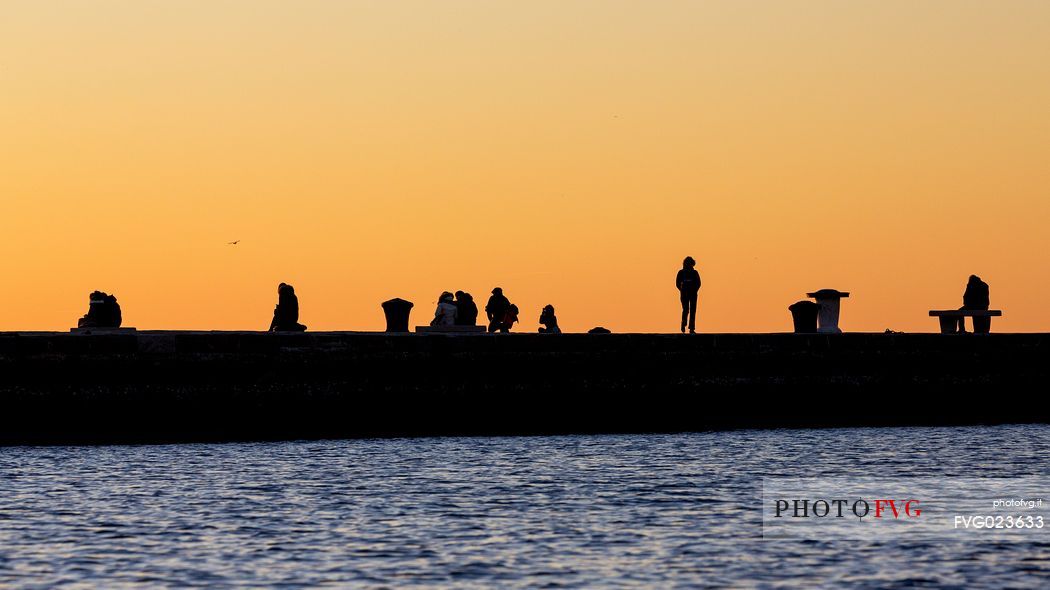 People on the Molo Audace at sunset, Trieste, Italy