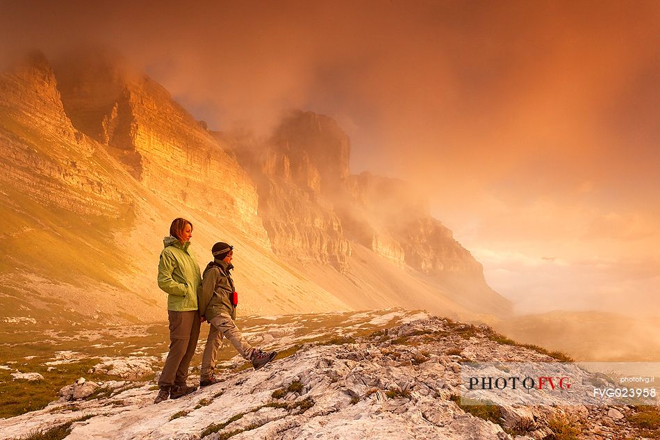 Hikers are looking the sunrise to dolomites of Brenta from Grost pass, Trentino, Italy