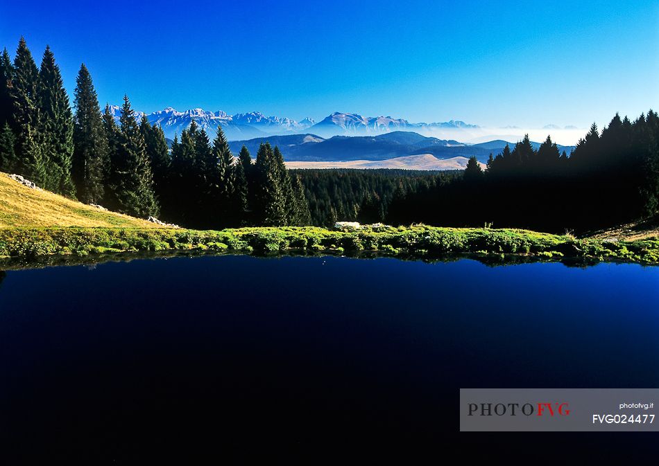 Lake at  Meletta di Gallio and in the background the dolomites, Asiago, Italy
