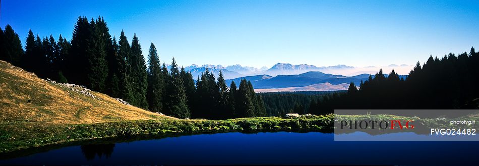 Lake at  Meletta di Gallio and in the background the dolomites, Asiago, Italy