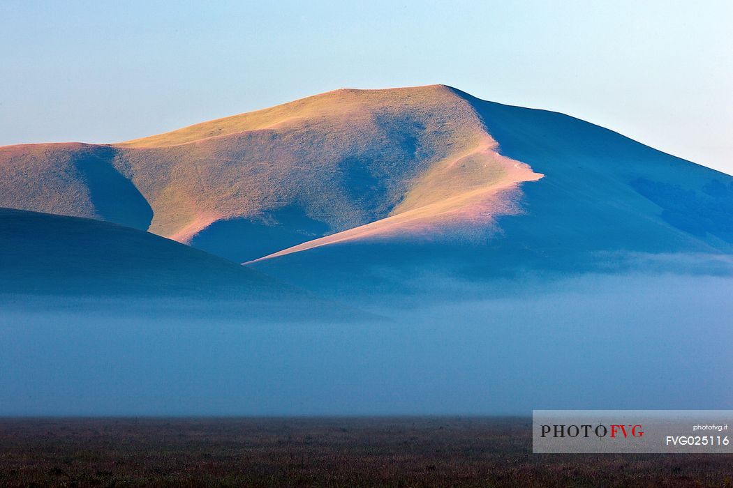 Fog and clouds at dawn on Sibillini meadows, Castelluccio di Norcia, Sibillini National Park, Italy