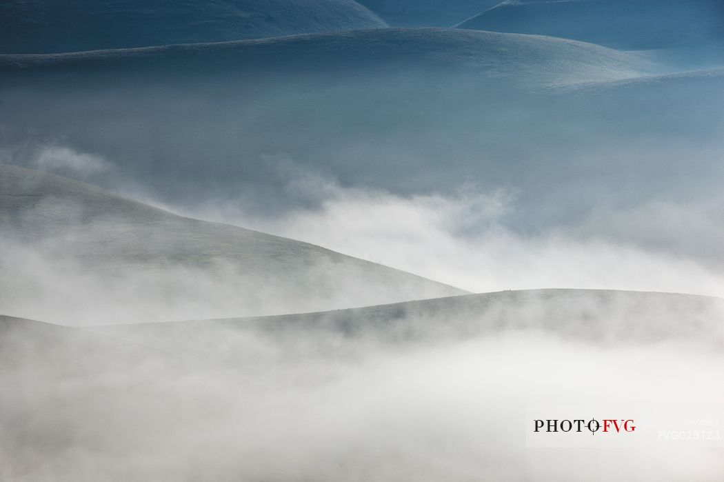 Fog and clouds at dawn on Vettore meadows, Castelluccio di Norcia, Sibillini National Park, Italy