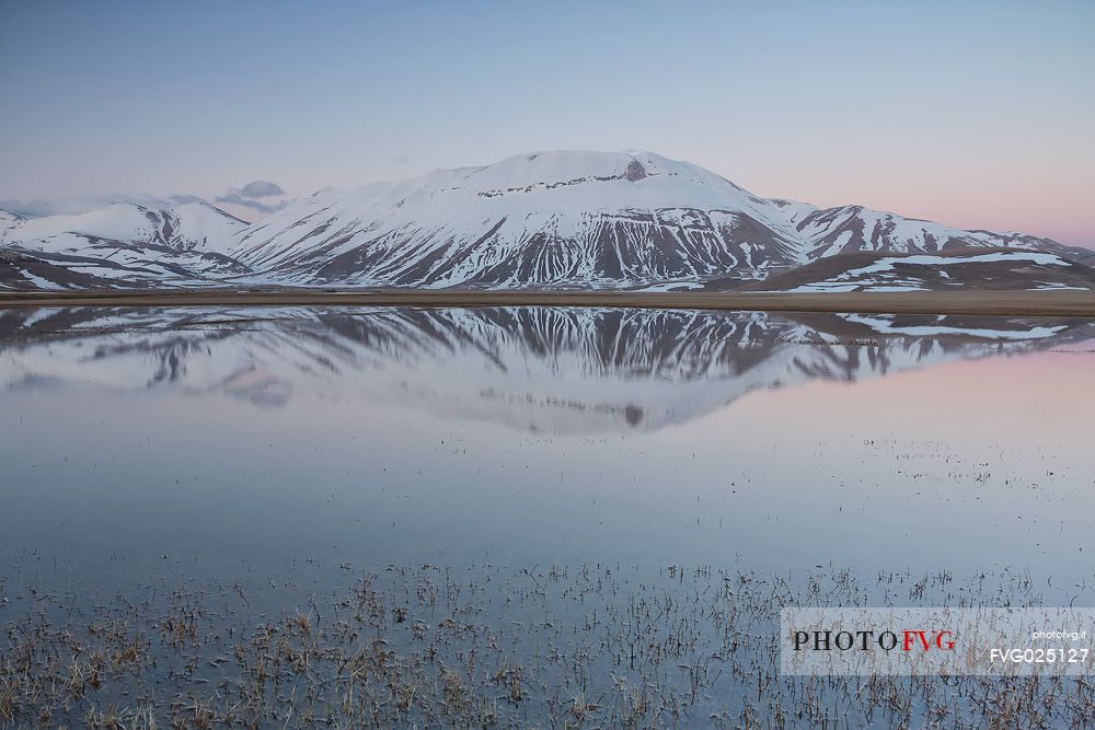 Thaw on the Pian Grande of Castelluccio di Norcia, in the background the Vettore mountain, Sibillini National Park