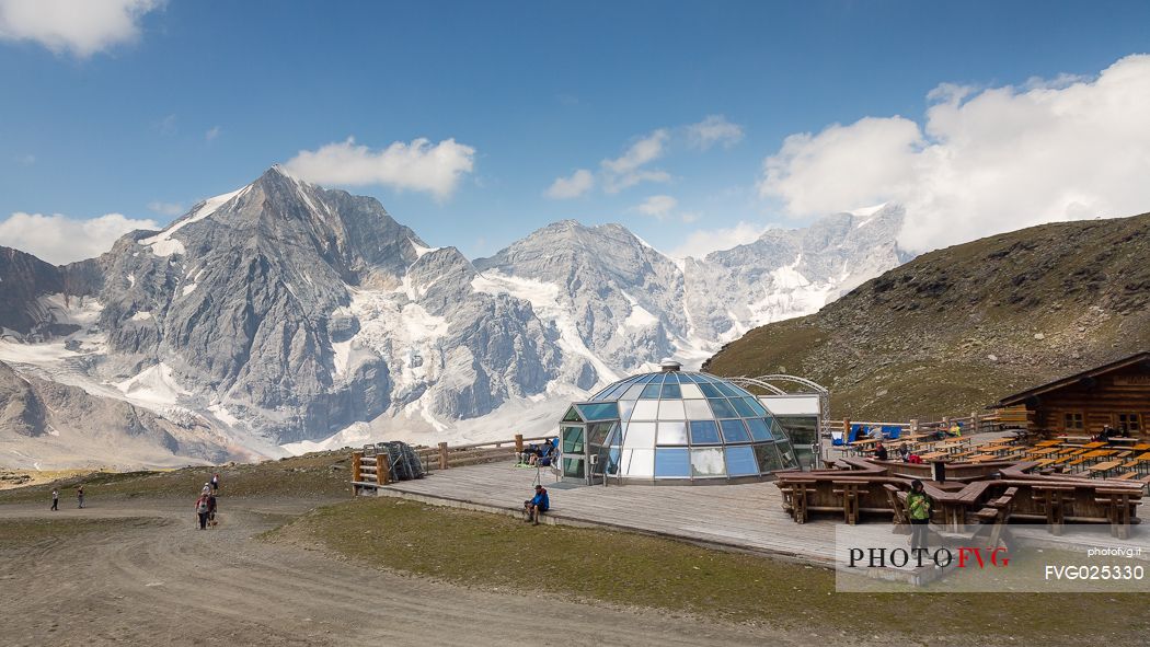 Hikers at Madriccio hut and in the background the Gran Zebr peak or Knig Spitze, Solda valley, Stelvio national park, South Tyrol, Italy