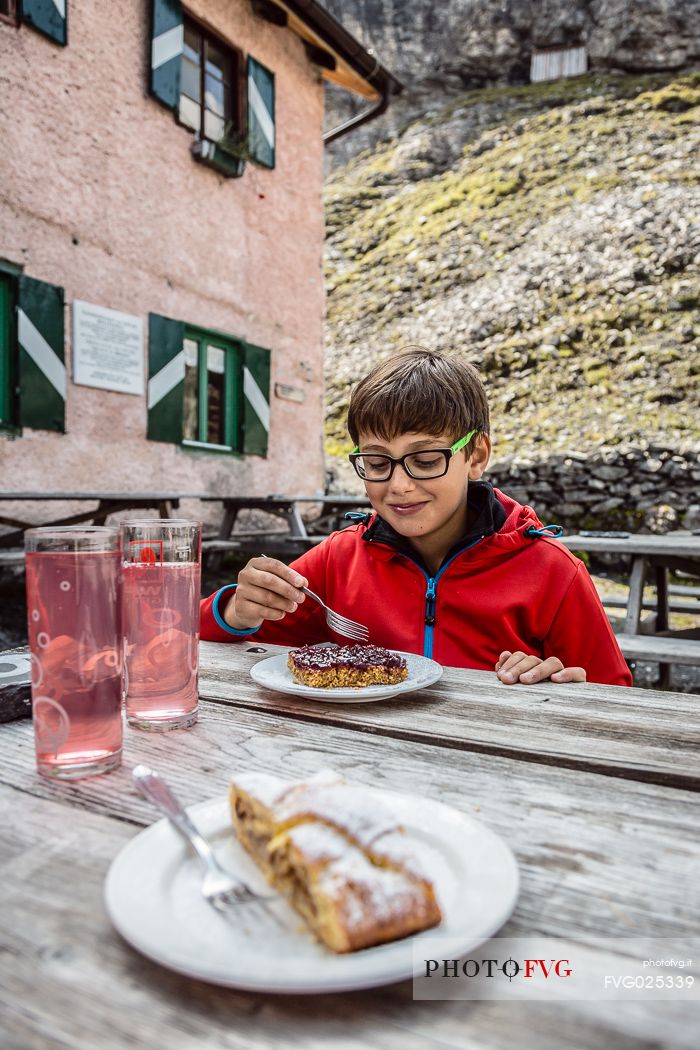 Young hiker eats a cake at Borletti hut, Venosta valley, Stelvio National Park, Italy
