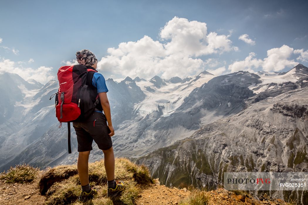 Young hiker near Passo dello Stelvio pass and in the background the Stelvio glacier, Passo dello Stelvio national park, Italy