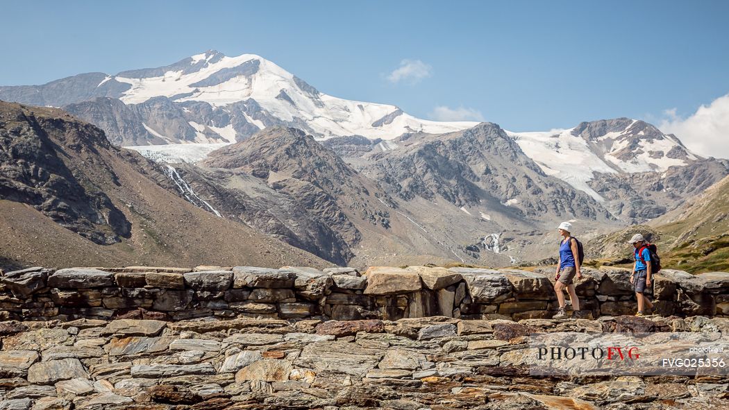 Hikers in high Martello valley and in the background the Cevedale glacier, Stelvio national park, Italy