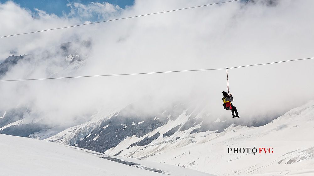 Tourist has fun on theAletsch glacier, floating on the steel cable over crevasses, Jungfraujoch, Berner Oberland, Switzerland, Europe