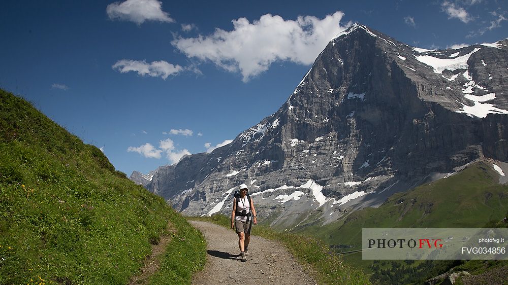 Hiker along the path from Mnnlichen to Kleine Scheidegg, in front of famous north face of Eiger mount, Grindelwald, Berner Oberland, Switzerland, Europe
 