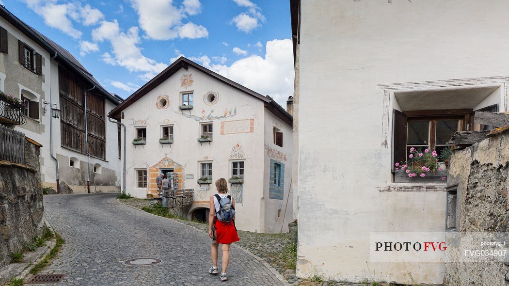 Tourist in the old road of Guarda a tipical village with houses ornated with old painted stone 17th Century buildings, Scuol, Engadine, Canton of Grisons, Switzerland, Europe