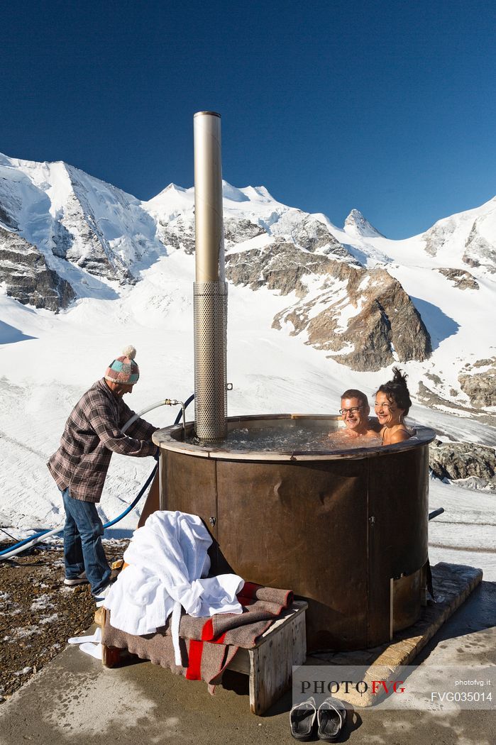 Tourists enjoing in the outdoor jacuzzi pool, in the background the Cresta Guzza, Bellavista and Piz Palu in the Bernina mountain range, Diavolezza Hut, Pontresina, Engadin, Canton of Grisons, Switzerland, Europe
 