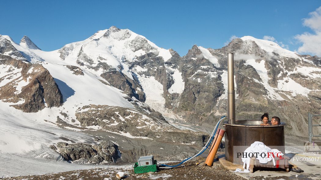 Tourists enjoing in the outdoor jacuzzi pool, in the background the Cresta Guzza and Piz Bernina peaks, Diavolezza Hut, Pontresina, Engadin, Canton of Grisons, Switzerland, Europe
 