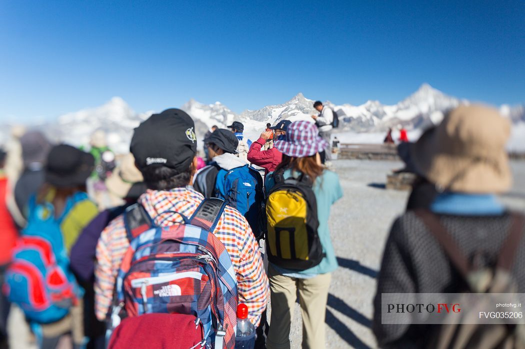Tourists in the top of Gornergrat admiring the Monte Rosa or Breithorn mountain range , Zermatt, Valis, Switzerland, Europe