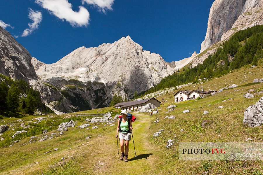 Hiker at the Ombretta hut, in the background the Ombretta peak and the south cliff of Marmolada, Rocca Pietore, dolomites, Veneto, Italy, Europe