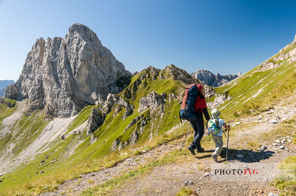 Mother and child walking in Sesis valley, in the background the Pic Chiadenis mount, Sappada, dolomites, Friuli Venezia Giulia, Italy, Europe