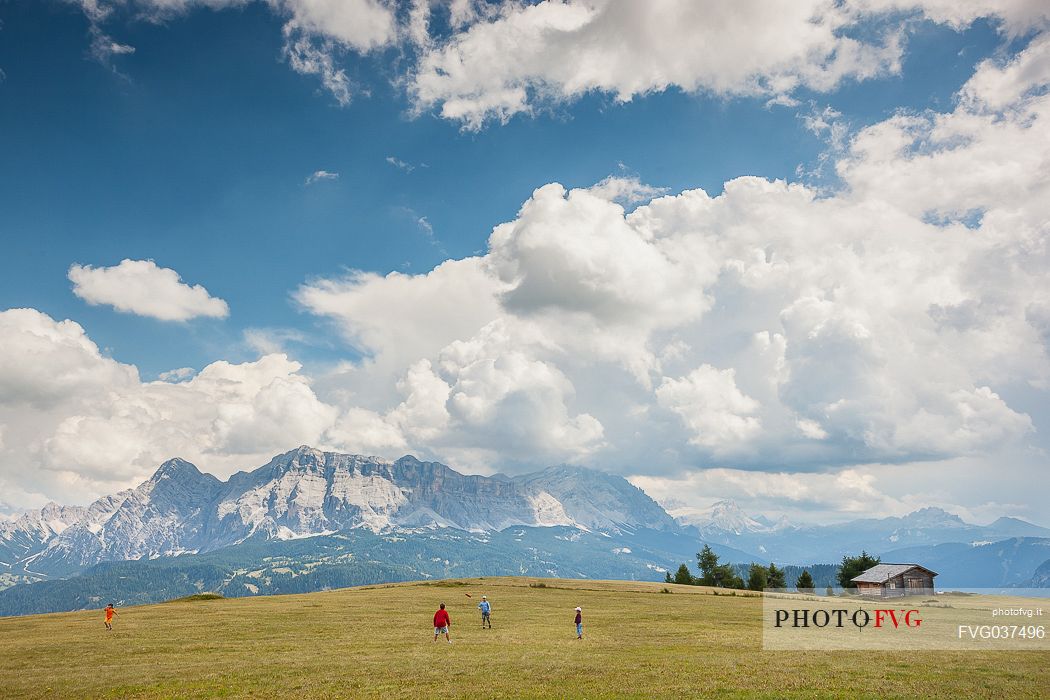 Children play on the high pasture of San Martino in Badia, in the background the Sasso della Croce and the Fanes dolomites,  Badia valley, South Tyrol, Italy, Europe