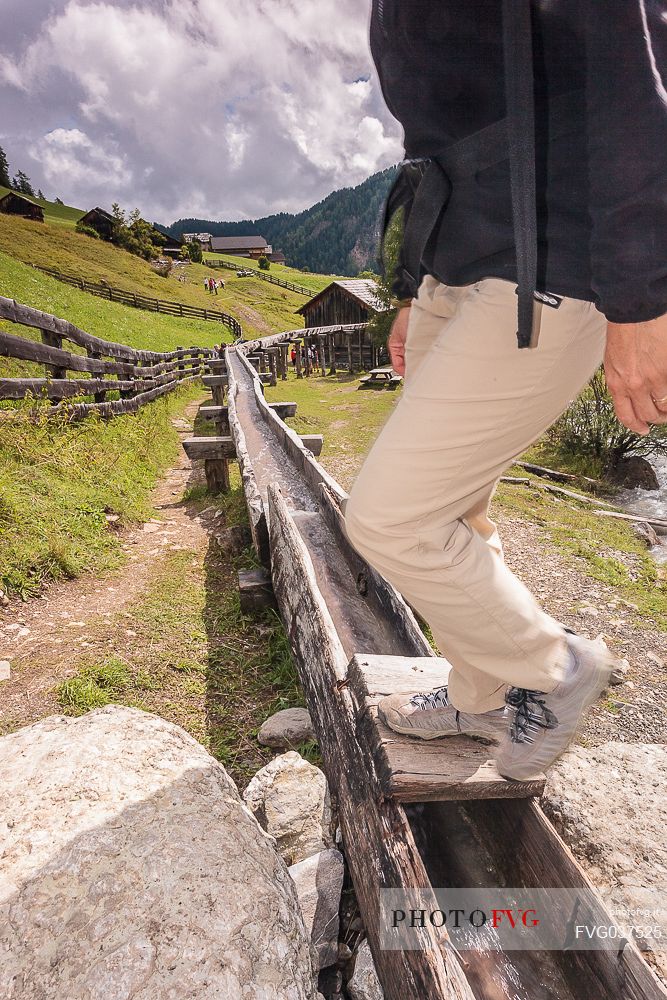 Hiker crosses the ancient wooden canal of water mill, Longiar, Badia valley, dolomites, Trentino Alto Adige, Italy, Europe