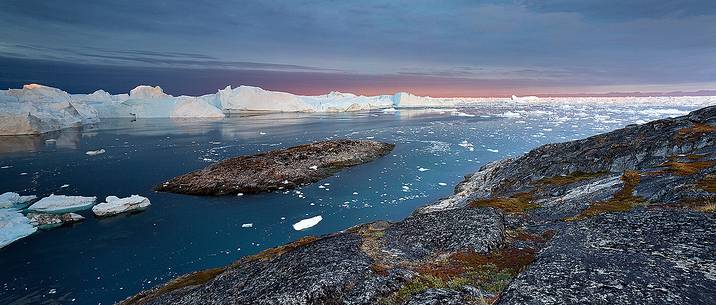 Moving ice in the water of Illulissat Fjord with the first morning light