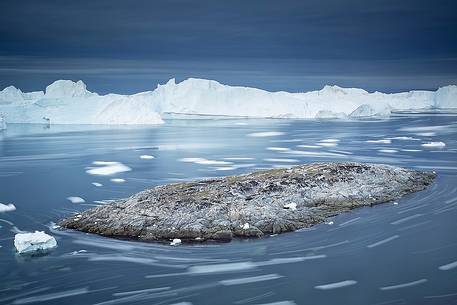 Moving ice in the water of Illulissat Fjord with the first morning light Moving ice in the water of Illulissat Fjord with the first morning light