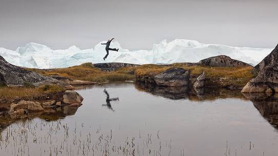 Hiking and action near a small pond; in the background icebergs in Kangerlua Fjord Hiking and action near a small pond; in the background icebergs in Kangerlua Fjord