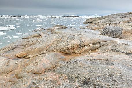 The reefs near the church of Illulissat town: in the background the moving ice of Illulissat Fjord The reefs near the church of Illulissat town: in the background the moving ice of Illulissat Fjord
