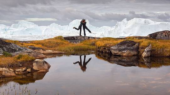 Hiking and action near a small pond; in the background icebergs in Kangerlua Fjord Hiking and action near a small pond; in the background icebergs in Kangerlua Fjord