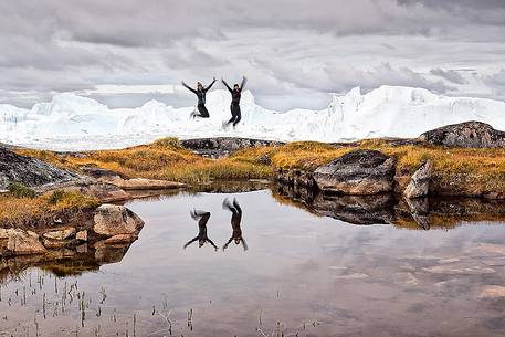 Hiking and action near a small pond; in the background icebergs in Kangerlua Fjord Hiking and action near a small pond; in the background icebergs in Kangerlua Fjord
