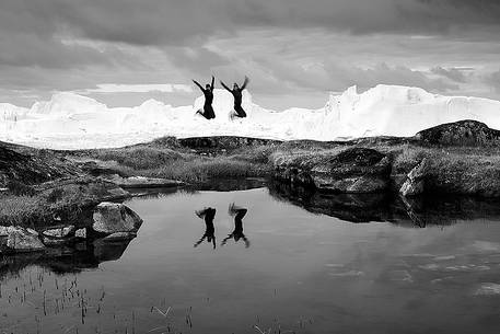 Hiking and action near a small pond; in the background icebergs in Kangerlua  Fjord