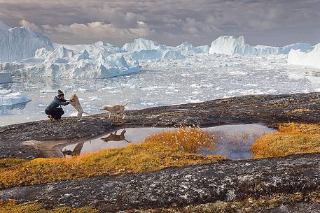 Hiking and action near a small pond; in the background icebergs in Kangerlua Fjord Hiking and action near a small pond; in the background icebergs in Kangerlua Fjord