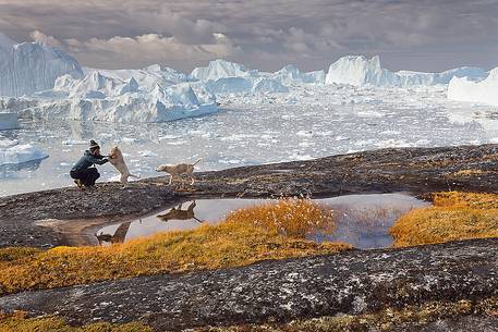 Hiking and action near a small pond; in the background icebergs in Kangerlua  Fjord