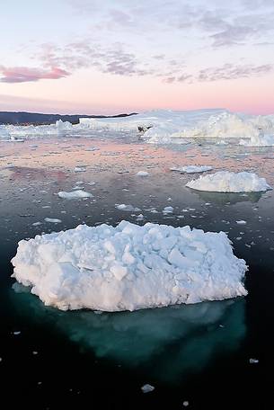 Moonlight over the icebergs of Kangerlua Fjord at dusk