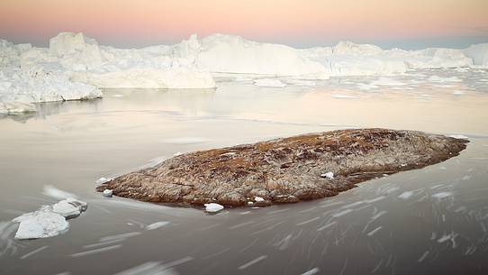 Moving ice in the water of Illulissat Fjord with the first morning light