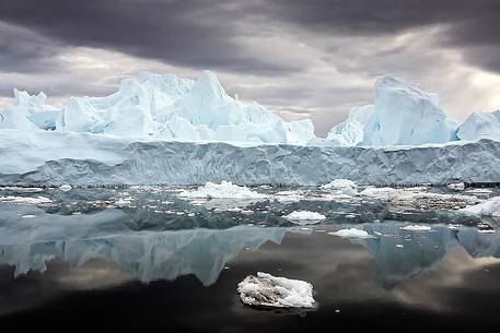 Reflections on sea of blue icebergs in Disko Bay