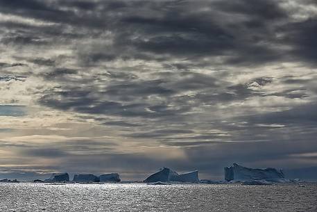 Dark clouds above blue icebergs in Disko Bay