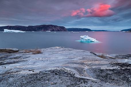 Pink clouds above iceberg in the sea in front  of Ataa a small village of fishermen and seal hunters which was abandoned in the 50s