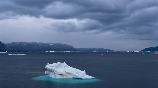 Dark clouds above iceberg in the sea in front  of Ataa a small village of fishermen and seal hunters which was abandoned in the 50s