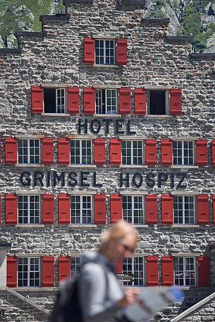 Tourist in front of Grimsel Hospice historic alpine hotel at Grimsel Pass, Bernese alps, Switzerland, Europe