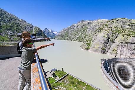 Tourists looking the Spitallamm dam and Grimselsee or Grisel lake, Grimsel pass, Bernese alps, Switzerland, Europe