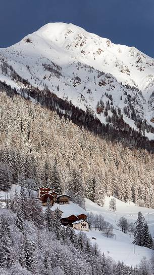 Typical mountain houses near Colle di Santa Lucia after an intense snowfall