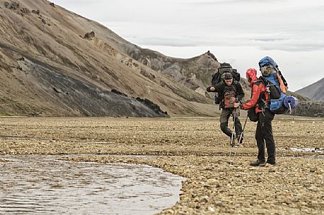 Young people hiking in multicoloured rhyolite mountain area of Landmannalaugar Young people hiking in multicoloured rhyolite mountain area of Landmannalaugar